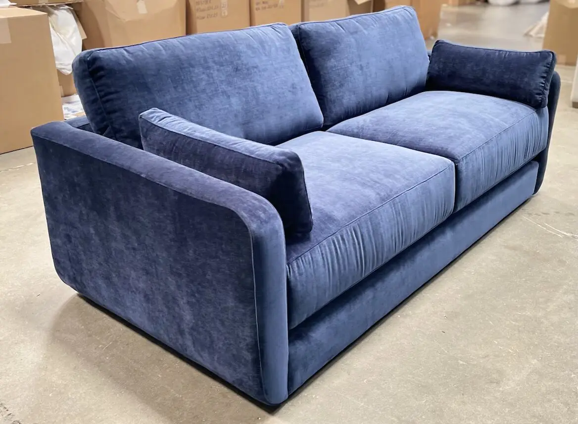Blue velvet three-seater sofa in warehouse