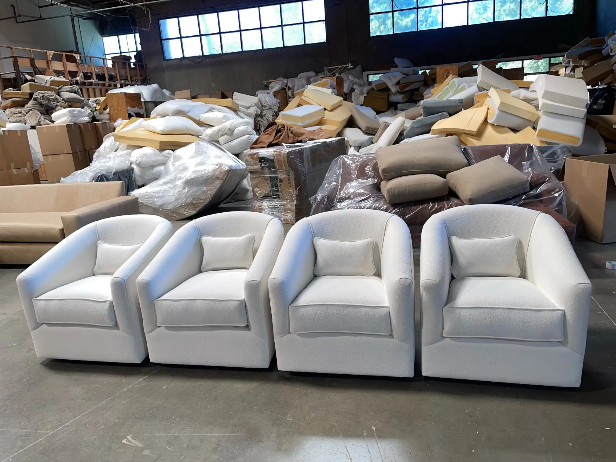 Four white upholstered armchairs in warehouse