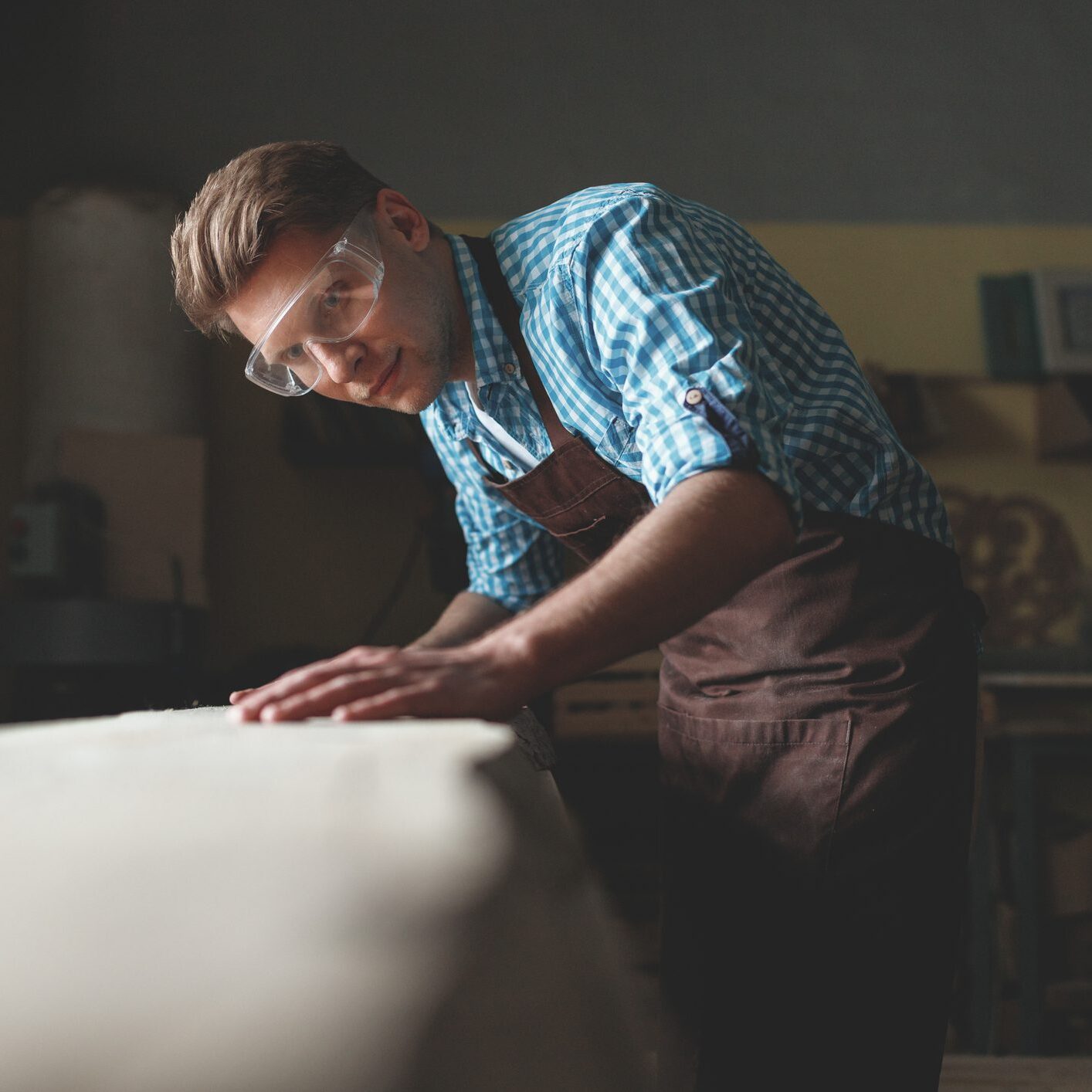 Carpenter sanding wooden tabletop in workshop